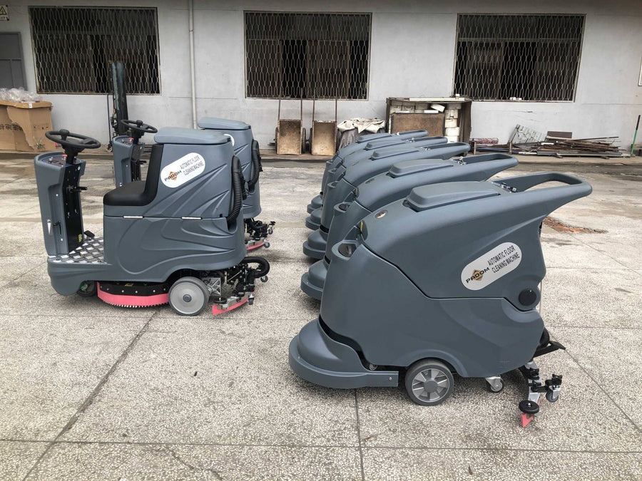 Multiple PADOM walk-behind and ride-on floor scrubber machines lined up outside the factory
