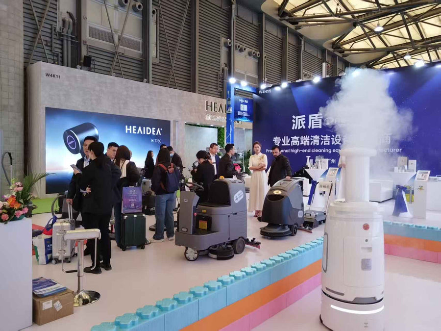 PADOM commercial cleaning equipment exhibition booth with vacuum cleaners, floor machines, and customers viewing professional cleaning products.